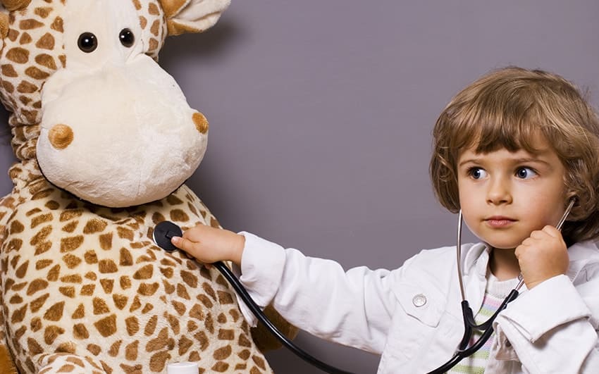 Young child playing doctor with a giraffe
