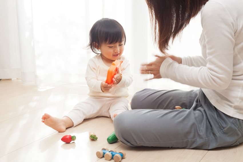 Nanny and young toddler playing with toys on the ground