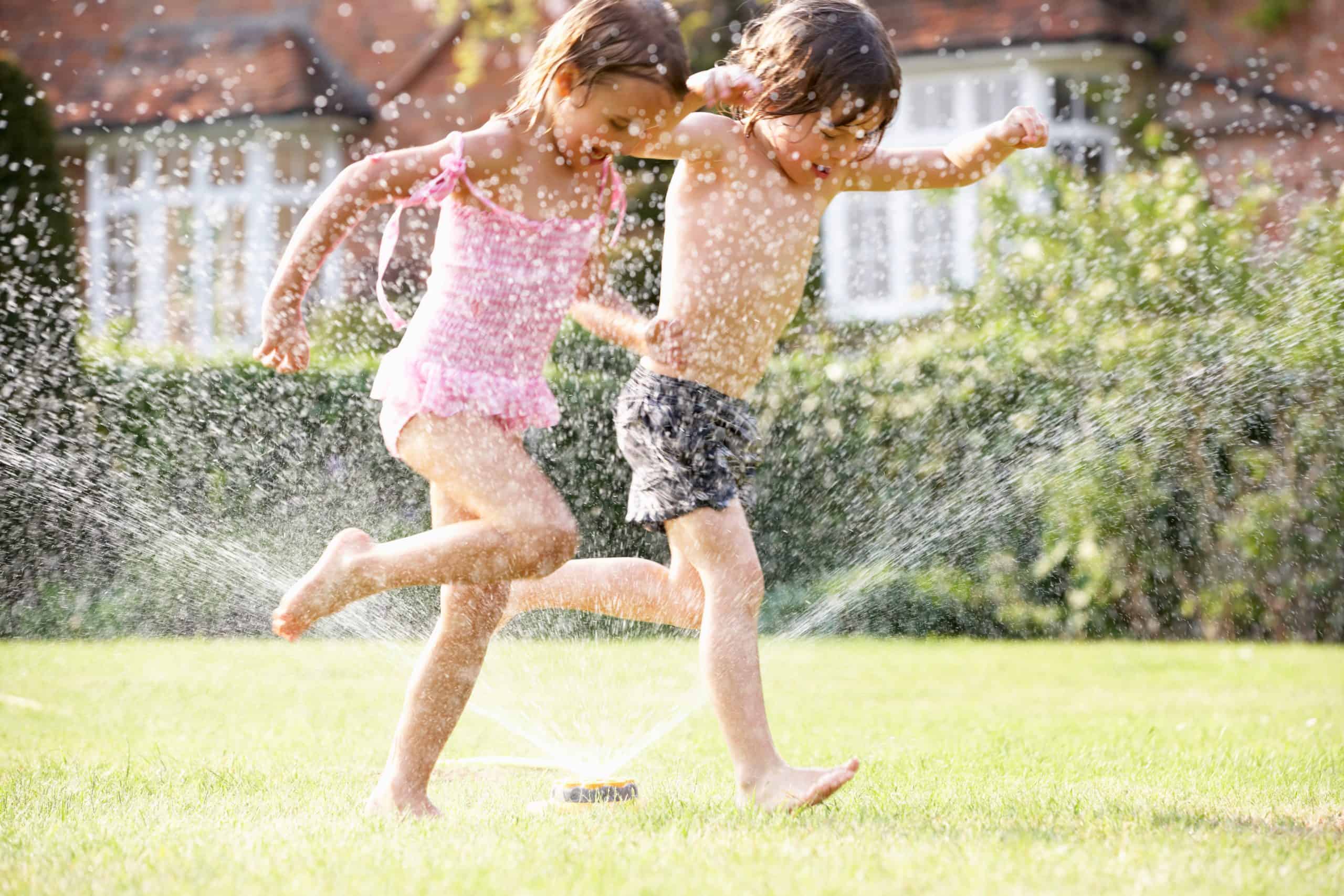 Two children running through a sprinkler – job Two children running through a sprinkler