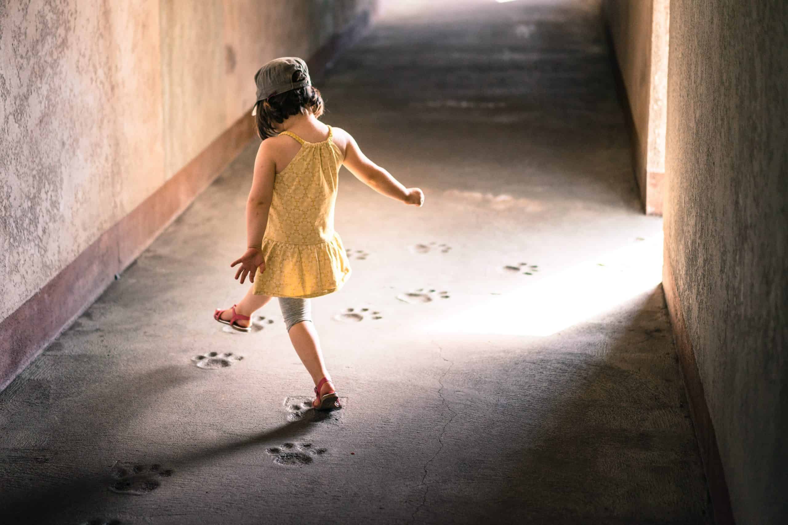 Little girl in a yellow top stepping on footprints – job Little girl in a yellow top stepping on footprints