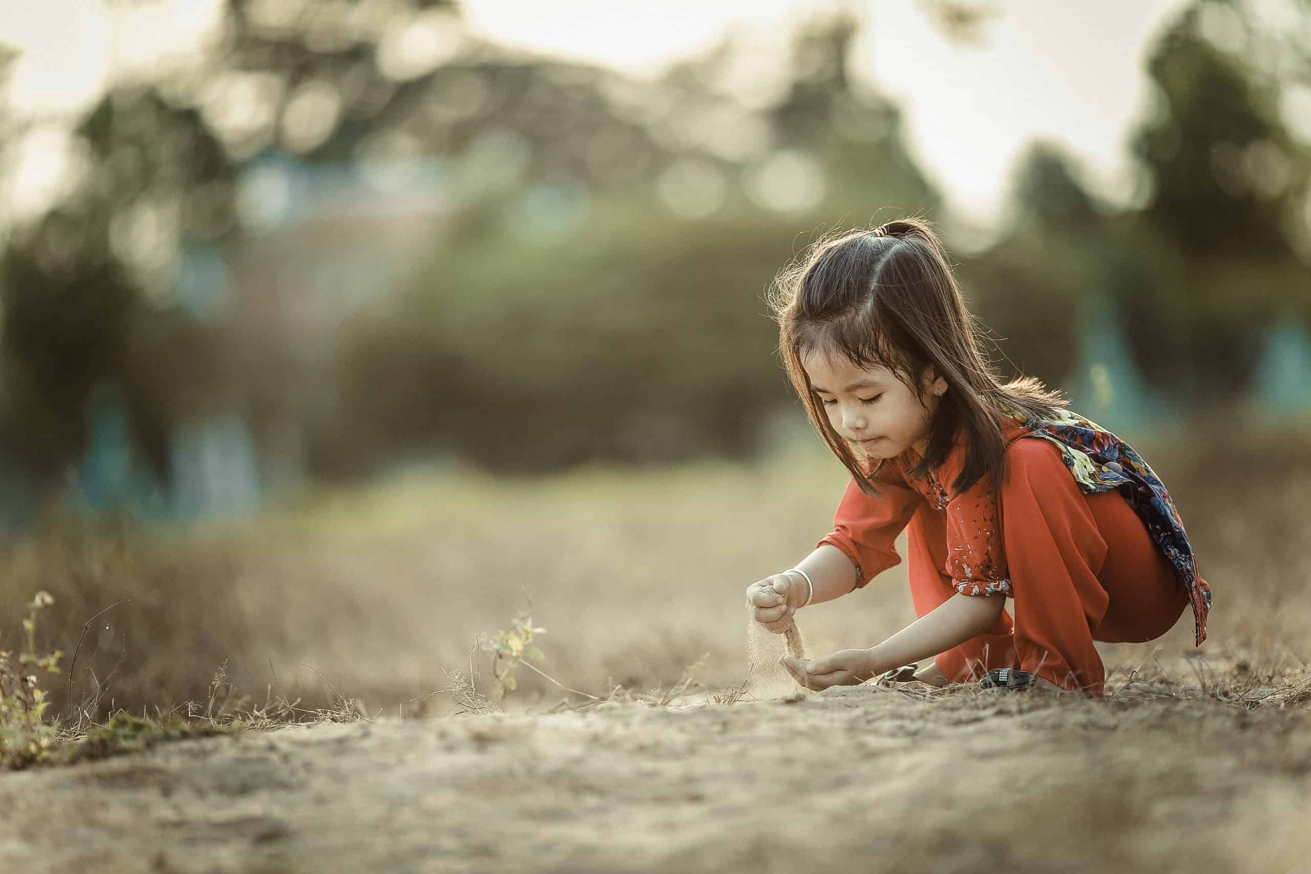 Little asian girl playing in sand