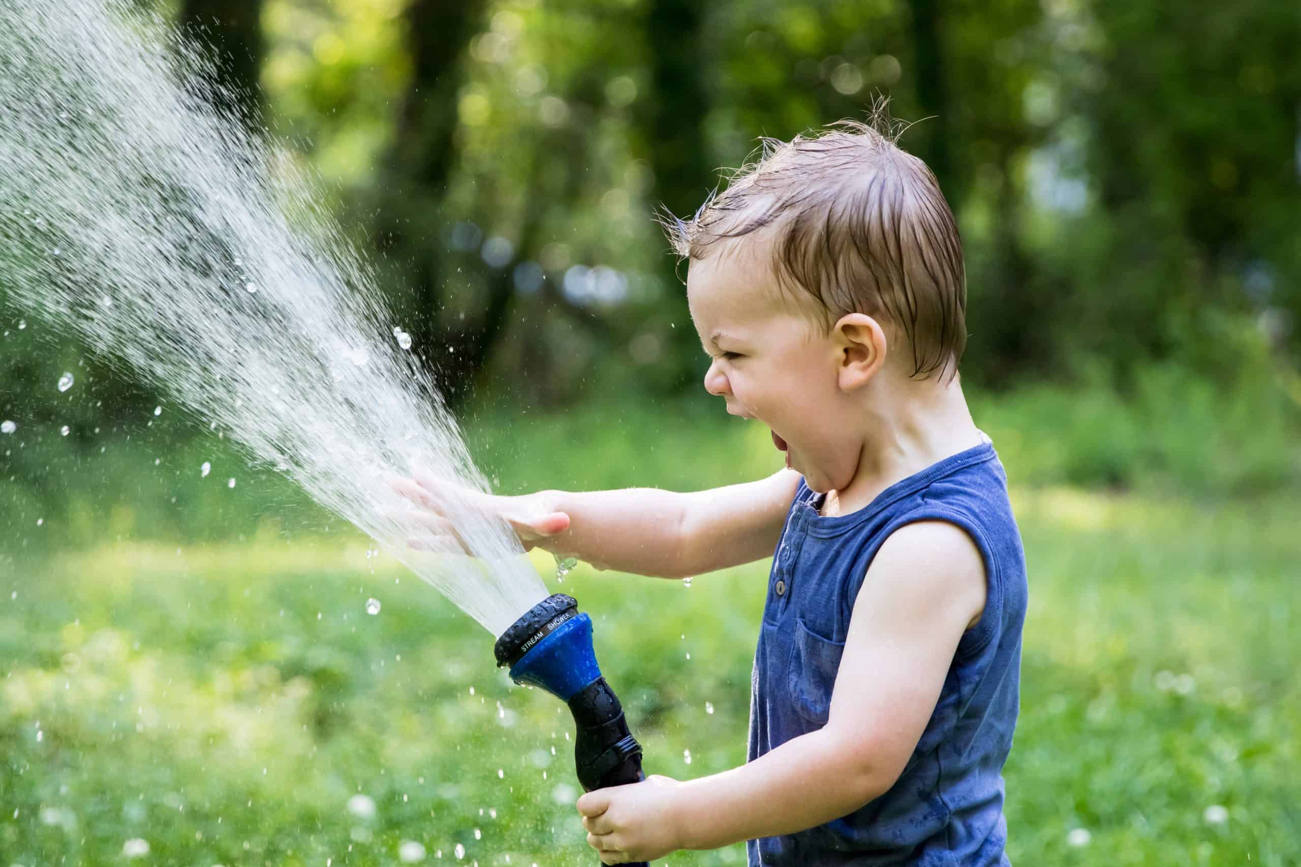 Little boy holding the hose outside