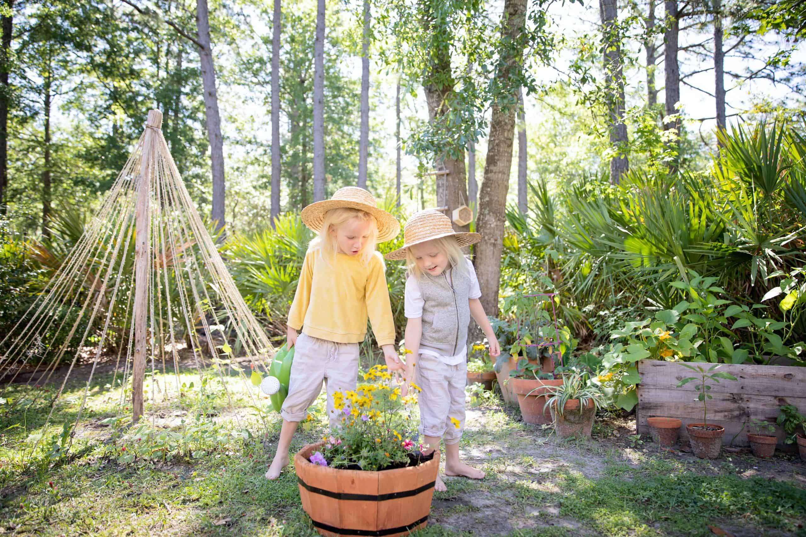 Two kids wearing straw hats – job Two kids wearing straw hats and looking at flowers in a circular planter outside - ROTA Nanny
