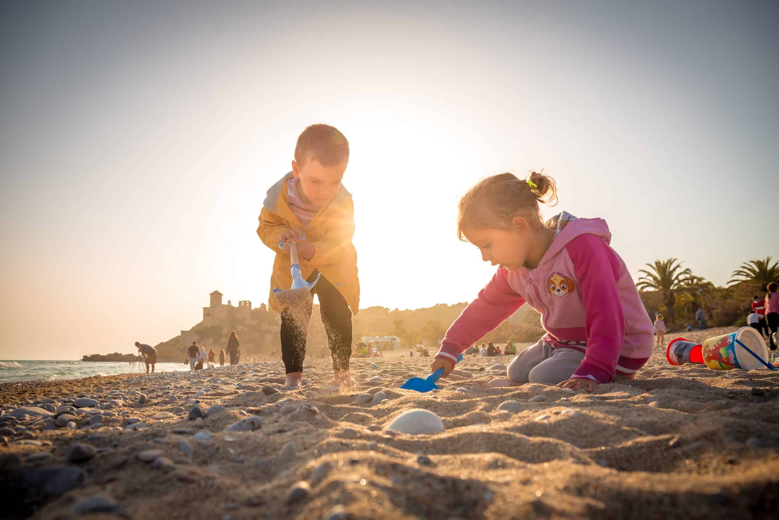 Two children playing in the sand – job Two children playing in the sand at the beach