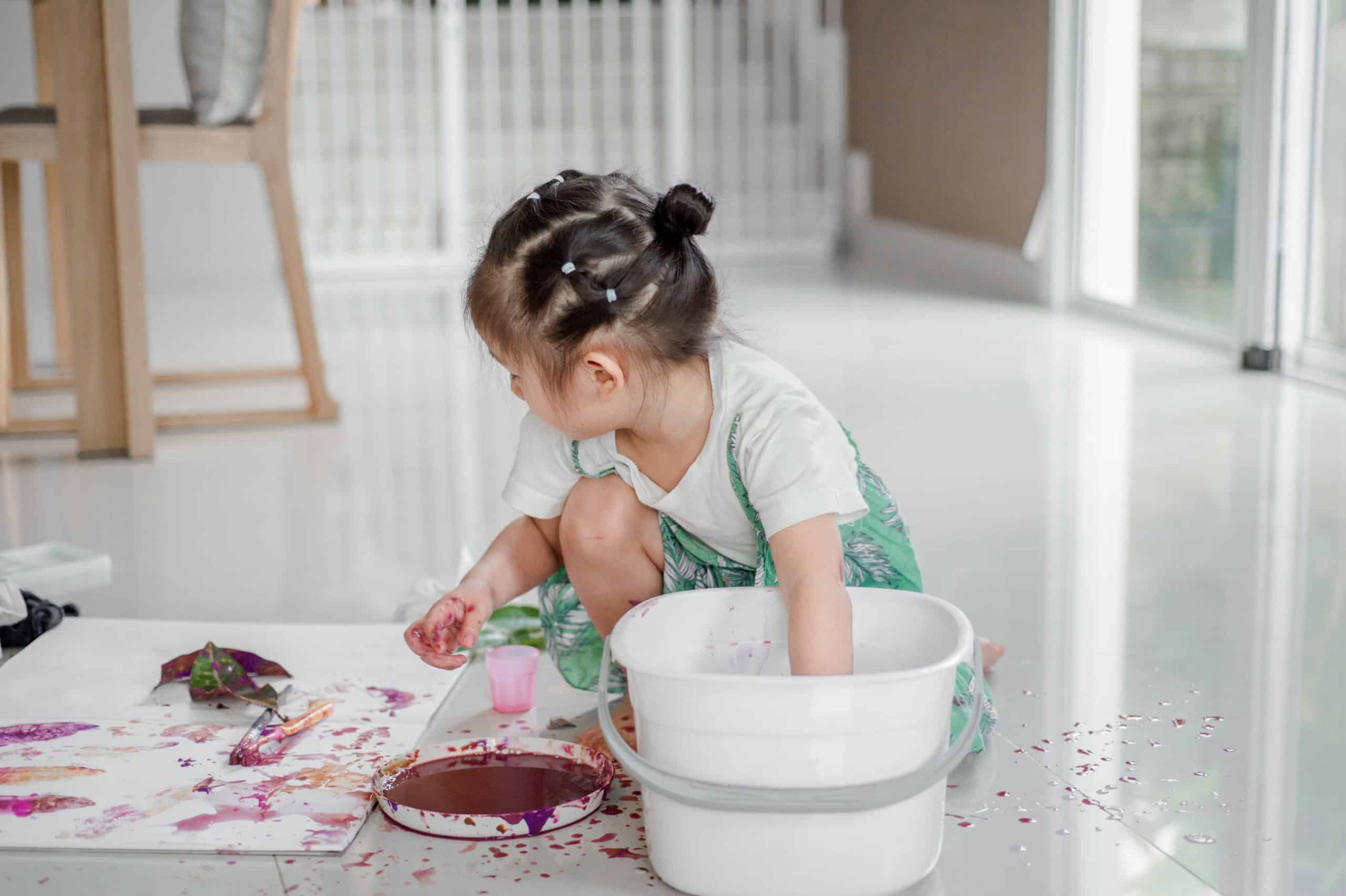 A little girl painting – job A little girl painting and making a mess on the floor