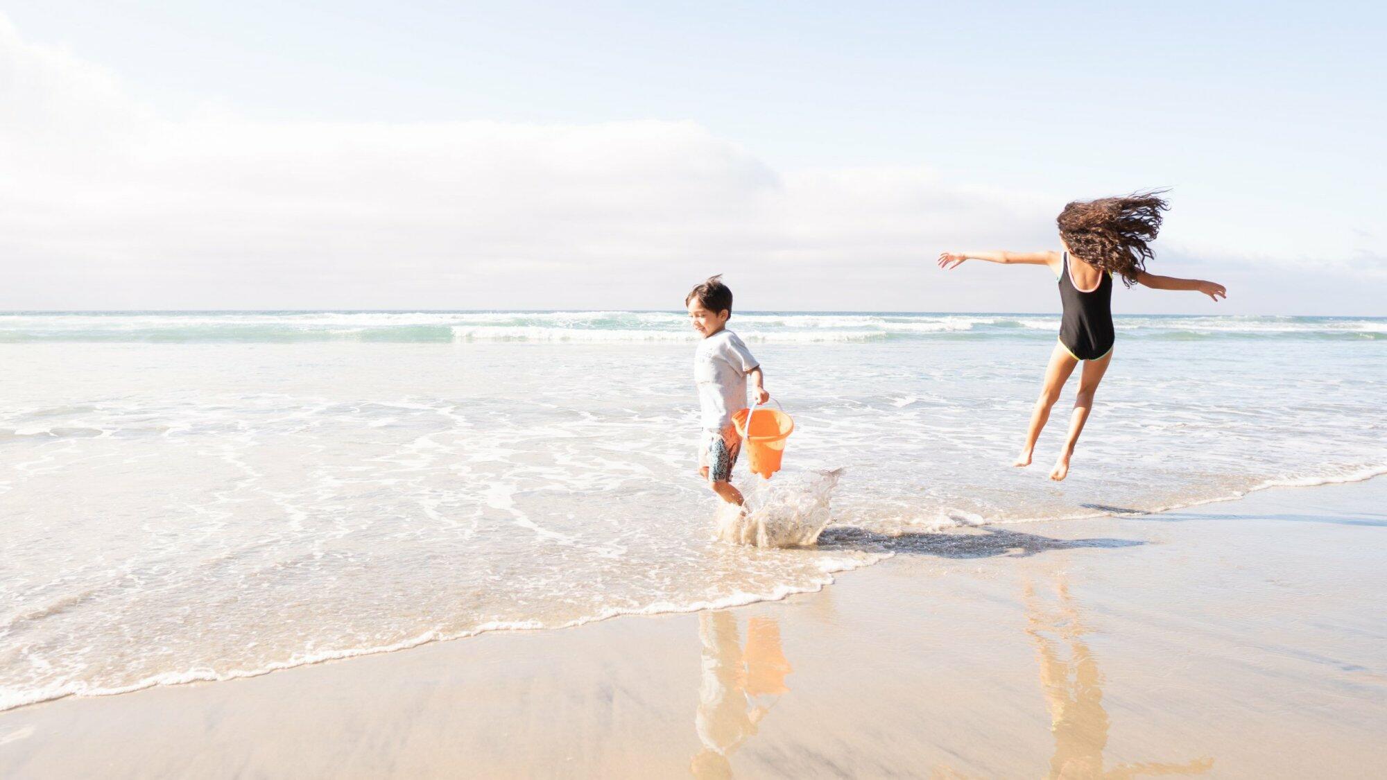 Two children playing in the water at the beach – job Two children playing in the water at the beach