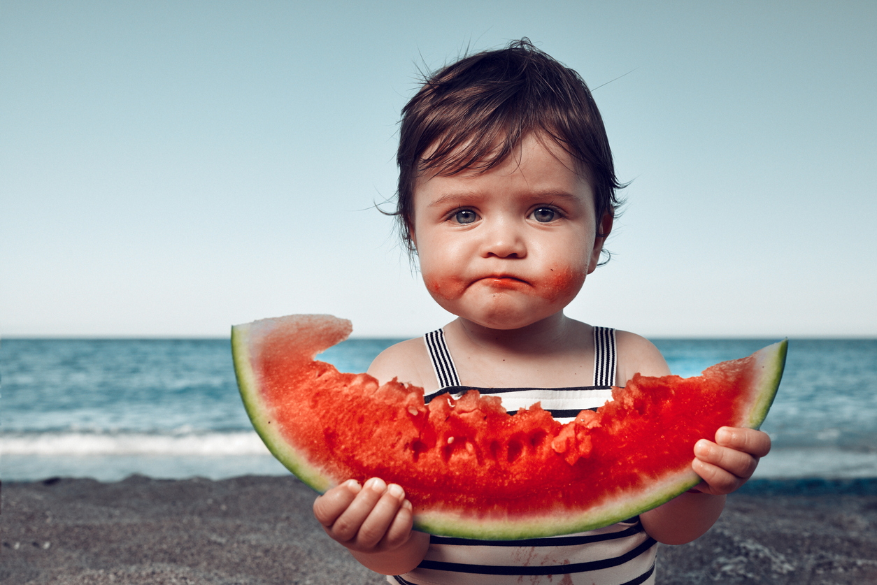 Watermelon girl -job A little toddler girl on the beach eating watermelon and making funny face.