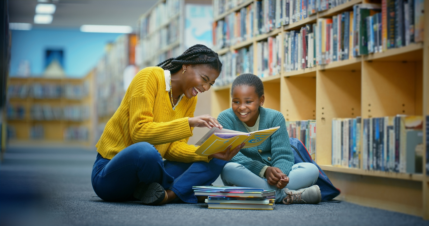A little girl and woman at the library reading a funny book