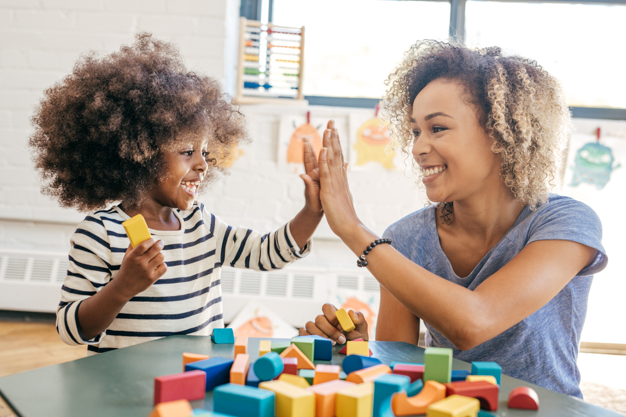 High five teacher and toddler with wooden blocks