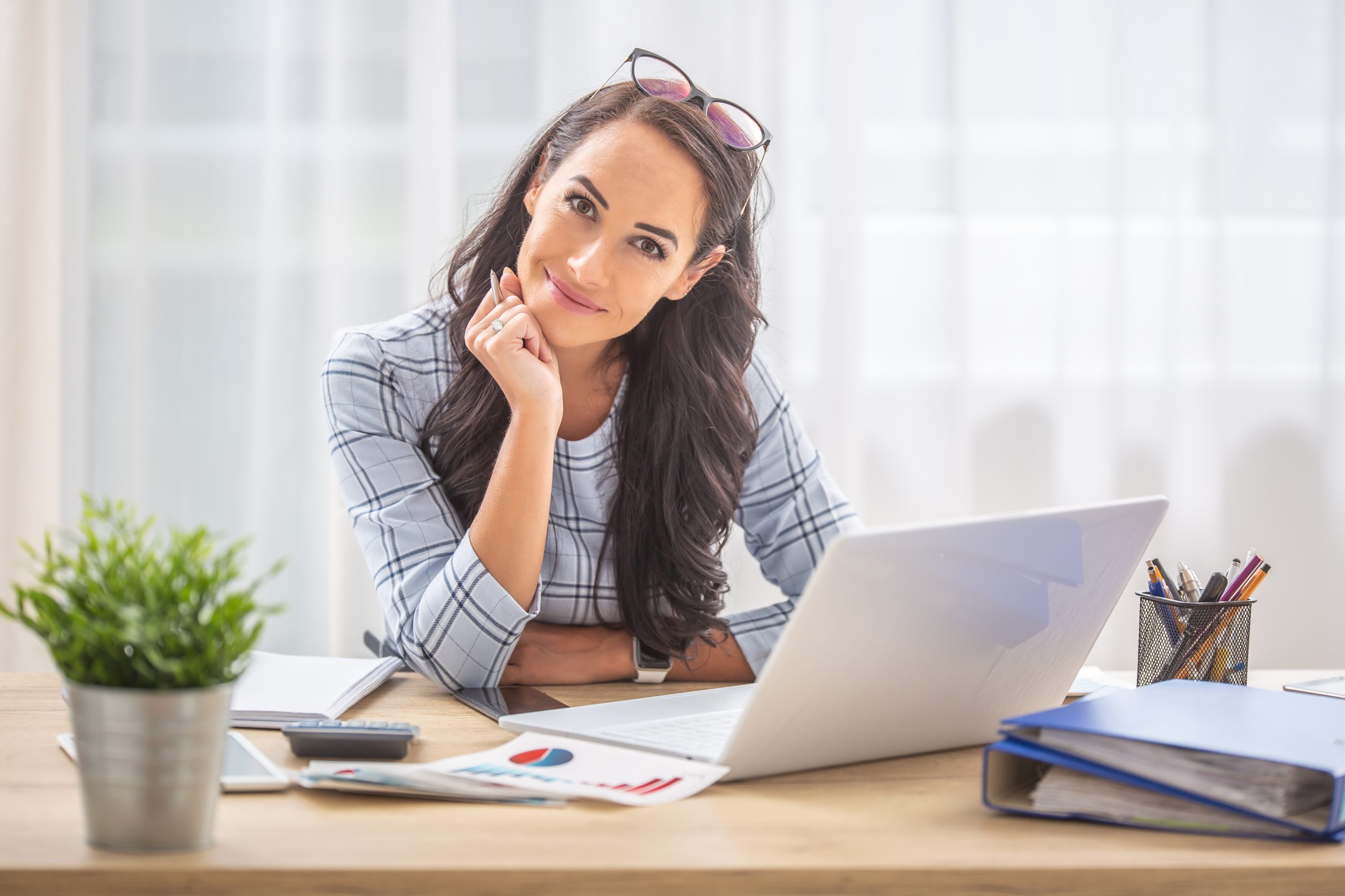 Smiling,Woman,With,Titled,Head,Leaned,On,Her,Hand,Sitting Family Assistant smiling at desk
