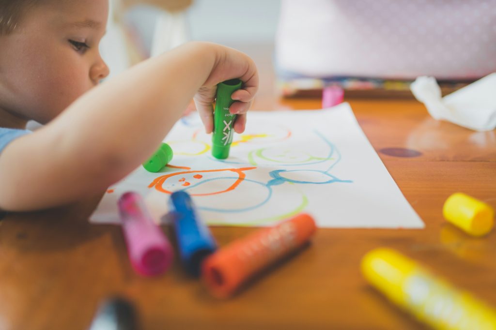 Child at a table doing a craft with markers