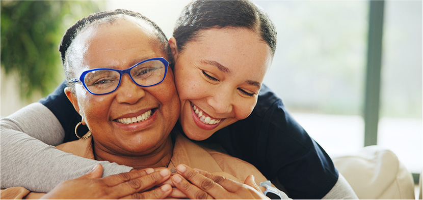golden era care provider embraces her happy client, older woman with glasses