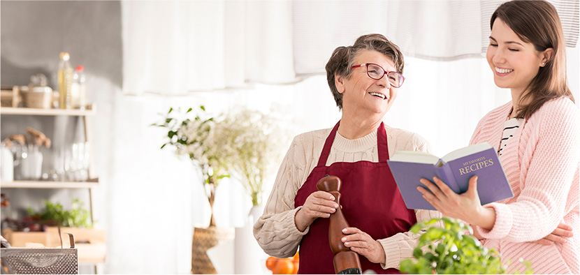 golden era care elder companion is cooking from her clients recipe book while her client helps engage in the kitchen tasks, everybodys happy